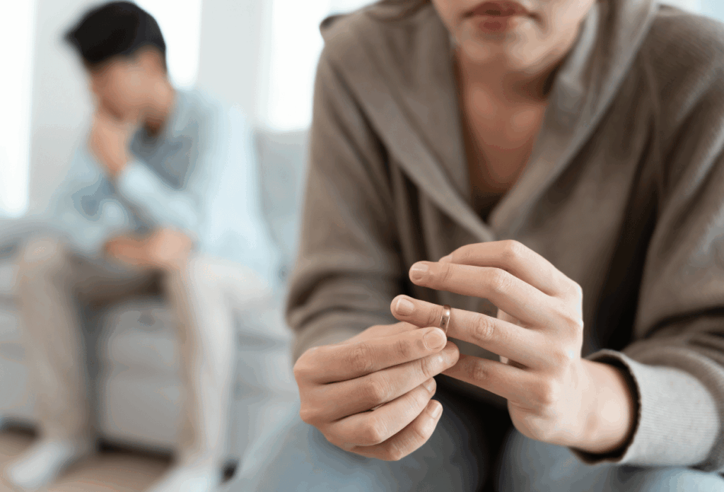 couple in frame sitting apart. One person is messing with their wedding ring